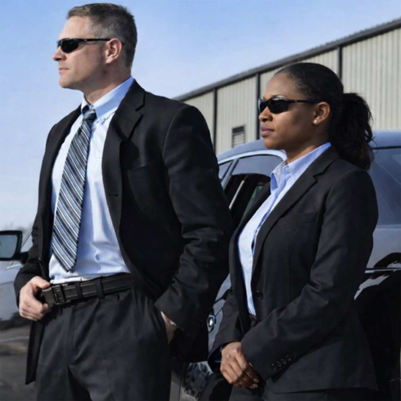 Male and female executive protection agents from Guardion Protection in professional suits and sunglasses, providing close protection and private security services.